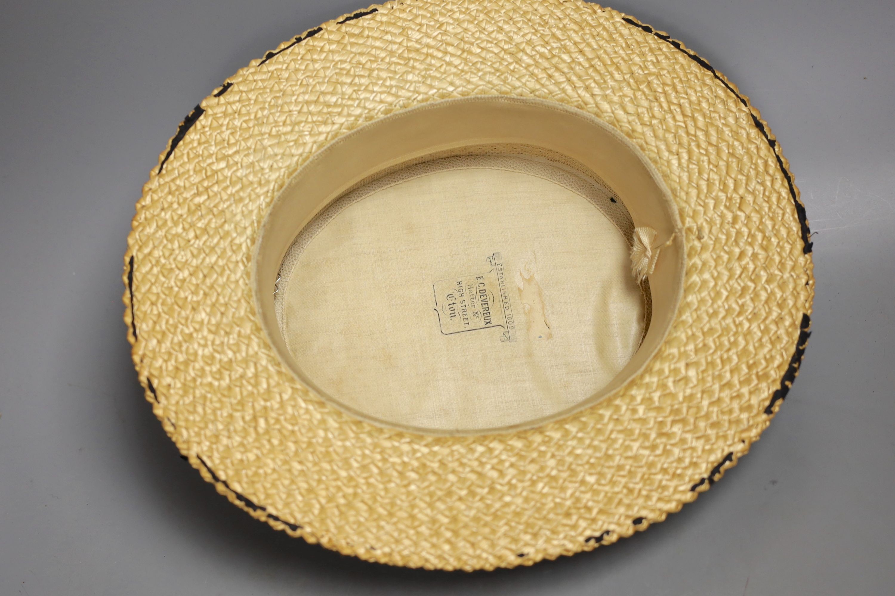 A straw boater, with crested badge and ribbon printed with ‘Alexandra’, 32 cms front to back including brim.
